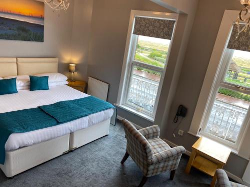 a bedroom with a bed and a chair and two windows at Furzedown Hotel in Great Yarmouth