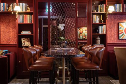a bar with leather chairs and a table and bookshelves at Sun Street Hotel Shoreditch in London