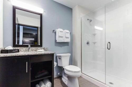 a bathroom with a toilet and a shower with a mirror at MainStay Suites Winfield-Teays Valley in Hurricane
