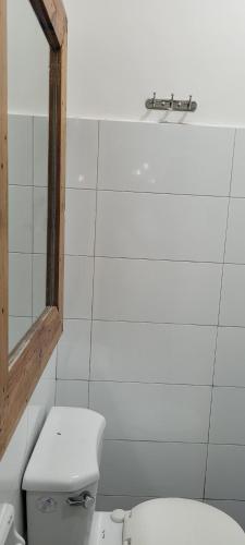 a white bathroom with a toilet and a mirror at Borj Place in Naga