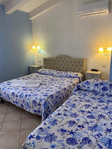 two beds in a room with blue and white sheets at Hotel Tabby in Golfo Aranci
