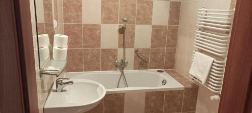 a bathroom with a bath tub and a sink at Hotel Przylesie in Sierosław