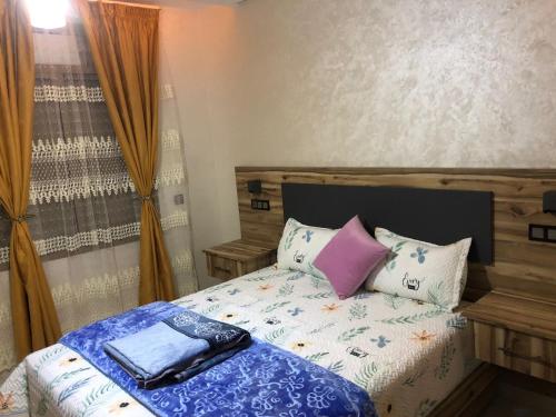 Un dormitorio con una cama con almohadas. en اقامة العائلة en Nador