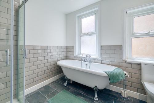 a white bathroom with a tub and a window at Brent House - 4 bedroom home close to shops, harbour & beaches in Ilfracombe