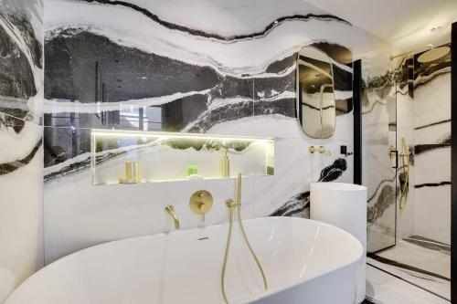 uma casa de banho com uma banheira branca e uma parede em preto e branco em Amazing Appart 3BR-6P - Bastille -Gare de Lyon 3 em Paris