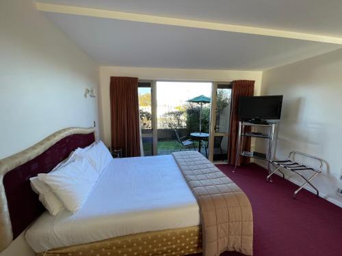 Habitación de hotel con cama y TV en Chantillys Motor Lodge, en Taupo