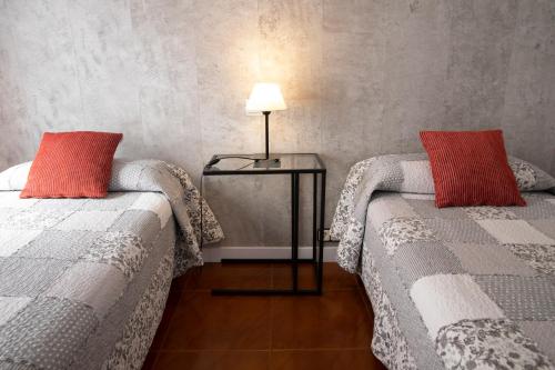 Habitación con 2 camas y mesa con lámpara. en Hostal Tokio, en Madrid