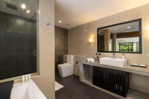 a bathroom with a sink and a toilet and a mirror at Thaala Bentota in Bentota