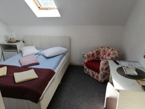 um pequeno quarto com uma cama e uma cadeira em CASA GRETA em Lupeni