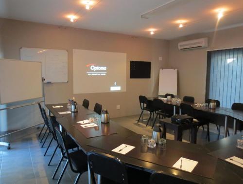 a conference room with tables and chairs and a screen at Club Cocomo in Hartbeespoort