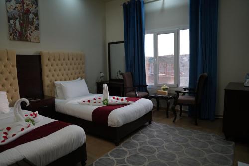Jabal Al Akhdar Grand Hotel في Jabal Al Akhdar: غرفة فندقية بسريرين ونافذة
