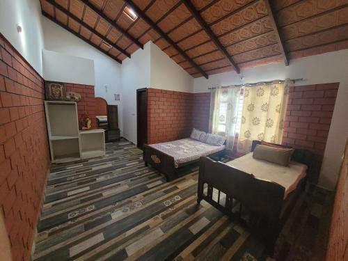 een kamer met 2 bedden en een bank. bij Aashirvada in Chikmagalūr