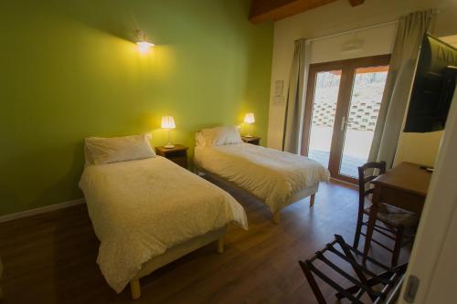 two beds in a room with green walls and a window at Albergo Diffuso Borgo Retrosi di Amatrice in Amatrice