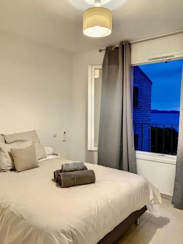 une chambre avec un grand lit blanc avec une fenêtre dans l'établissement Domaine a Mortella, à Saint-Florent