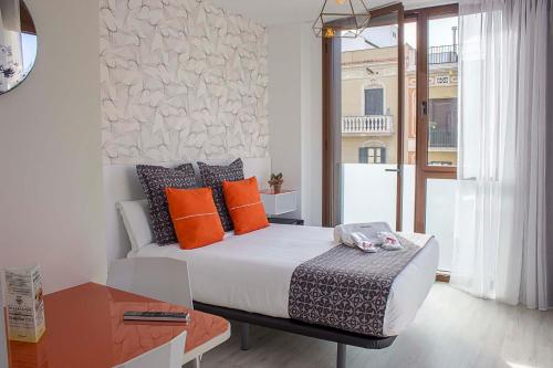 um quarto com uma cama grande e almofadas laranja em Apart-Suites Hostemplo em Barcelona