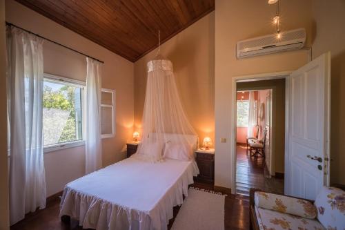 a bedroom with a white bed with a canopy at Riza Stone Cottage, romantic house, pet friendly in Vátos