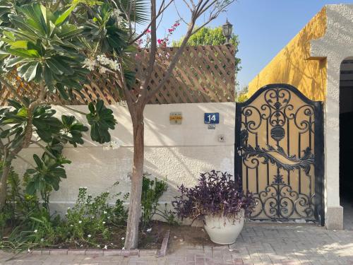 a gate to a house with a tree in front of it at Tropicana Guestroom 7 min walk from the beach in Dubai
