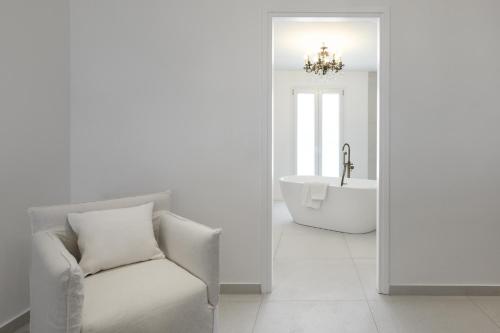 a bathroom with a tub and a chair and a sink at Kallisti Paros in Naousa