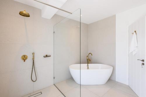 a bathroom with a tub and a glass shower at Kallisti Paros in Naousa