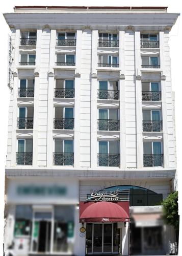a tall white building with a red awning at Bayazıt Hotel in İskenderun