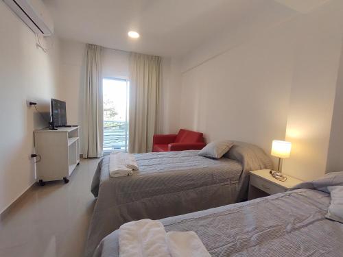 una camera d'albergo con due letti e una sedia rossa di DELFINA suites 2A a La Rioja