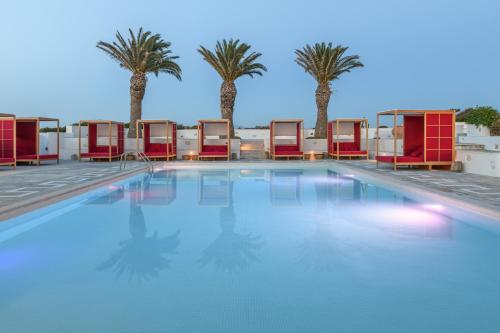 a swimming pool with chairs and palm trees at Kallisti Paros in Naousa