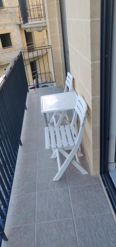 a pair of white chairs sitting on a balcony at Minute walk to the sea in Żebbuġ