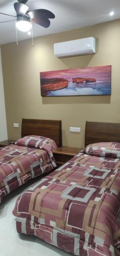 a bedroom with two beds and a painting on the wall at Minute walk to the sea in Żebbuġ