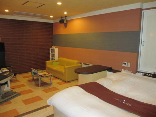 a hotel room with a bed and a yellow couch at ホテル アルファ in Iizaka