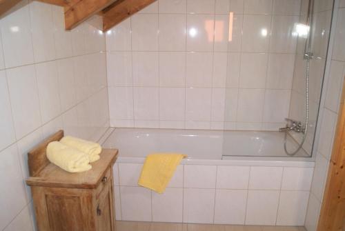La salle de bains est pourvue de carrelage blanc, d'une baignoire et d'une serviette jaune. dans l'établissement Großes Ferienhaus mit 5 Schlafzimmer & 4 Bäder, à Pöllauberg