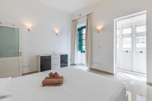 un asciugamano su un letto in una camera bianca di Unique Four Bedroom Townhouse One Minute Away From The Seafront a Sliema
