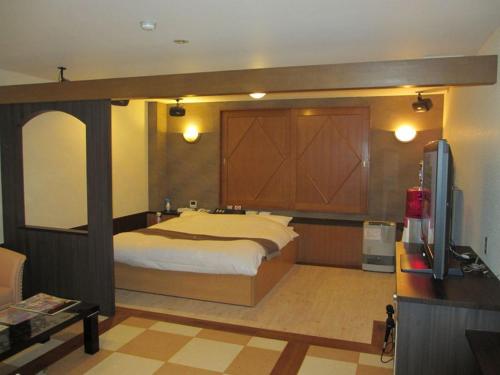 een slaapkamer met een bed en een tv. bij ホテル アルファ in Iizaka