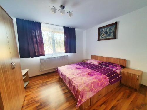 a bedroom with a bed with a purple comforter at Cabana Denisa in Rîu de Mori