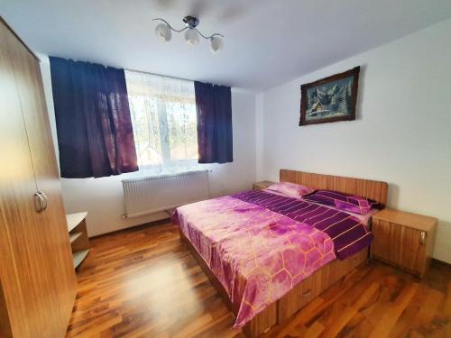 a bedroom with a bed with a purple comforter at Cabana Denisa in Râu de Mori