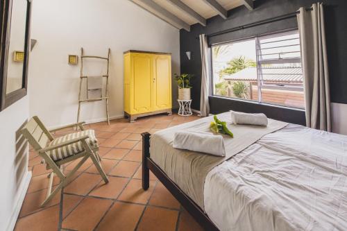 Cape Town Surf Hostel & Lodge في كيب تاون: غرفة نوم بسرير وكرسي ونافذة