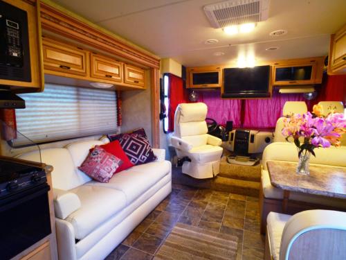 an rv living room with a couch and a tv at Luxury American RV with Hot Tub in West Chiltington