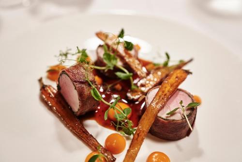 a plate of food with carrots and meat at Goldene Rose Karthaus a member of Small Luxury Hotels of the World in Senales