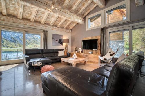 een woonkamer met een leren bank en een tv bij Chalet Ancolie in Tignes