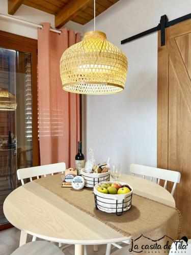 a dining room table with bowls of fruit and a chandelier at La Casita de Tila in Ifonche