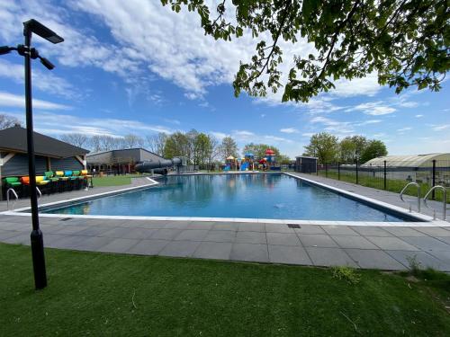 a large swimming pool with a playground in a park at LUXUS Cube Ferienhaus Chalet am See mit Schwimmbad in Lathum NL in Lathum