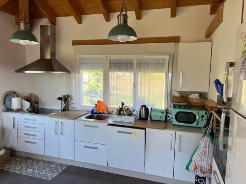 eine Küche mit weißen Schränken und einer Mikrowelle in der Unterkunft A Casa do Portal in Campo Lameiro