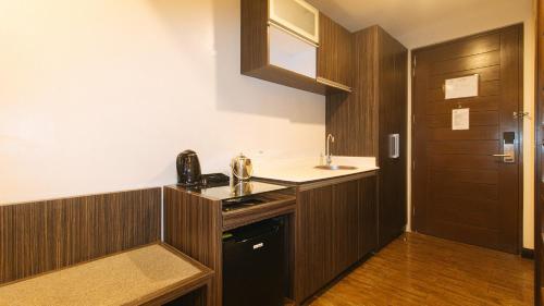 a kitchen with wooden cabinets and a sink and a door at RedDoorz Premium @ West Avenue Quezon City in Manila