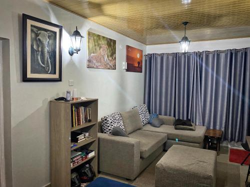 a living room with a couch and a book shelf at Tranquil One Bedroom - Karen in Nairobi
