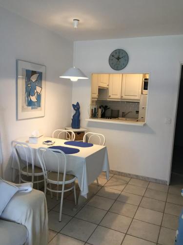 une cuisine avec une table et des chaises et une horloge au mur dans l'établissement Nice 36 m with balcony and pool near beaches, à Antibes