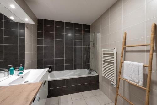 une salle de bain avec un lavabo et une baignoire dans l'établissement Bluemary - Spacieux T3 Garage balcon, à Lyon