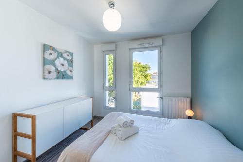 um quarto com uma cama branca e 2 janelas em Bluemary - Spacieux T3 Garage balcon em Lyon