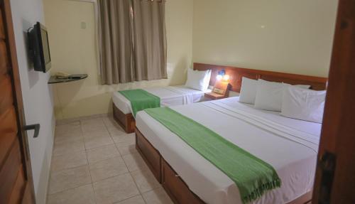 a hotel room with two beds and a television at Boulevard da Praia Flats in Porto Seguro