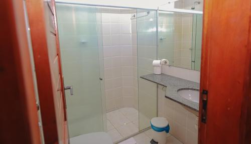 a bathroom with a glass shower and a sink at Boulevard da Praia Flats in Porto Seguro
