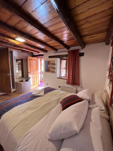 a large bed in a room with wooden ceilings at Casona les Pleiades in Cusco