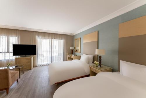 a hotel room with two beds and a flat screen tv at Mövenpick Resort Petra in Wadi Musa